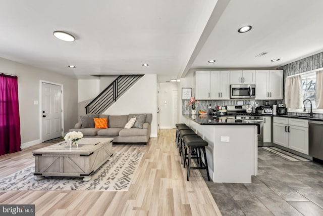 kitchen with a breakfast bar area, white cabinets, sink, and stainless steel appliances