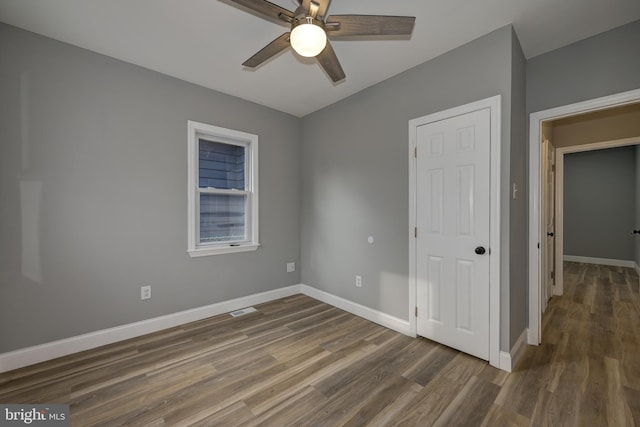 unfurnished bedroom with ceiling fan and dark hardwood / wood-style flooring