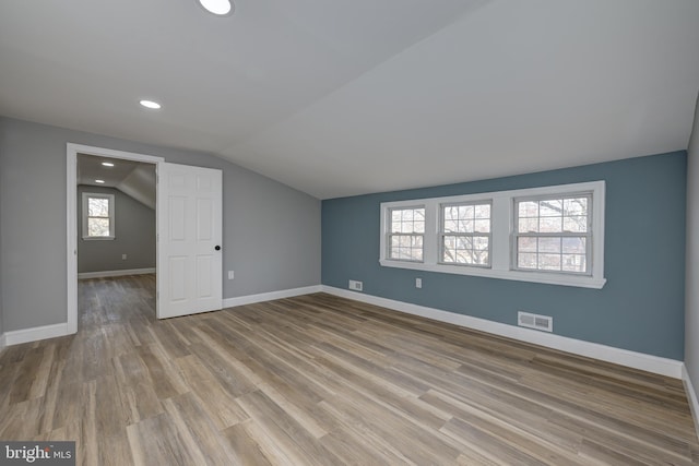 additional living space featuring light wood-type flooring and lofted ceiling