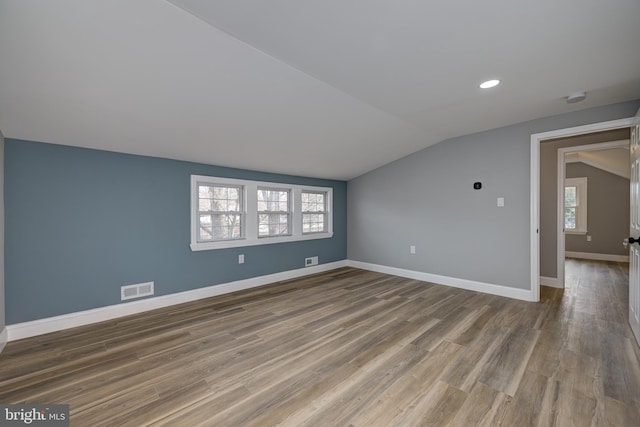 bonus room with a wealth of natural light, lofted ceiling, and hardwood / wood-style floors