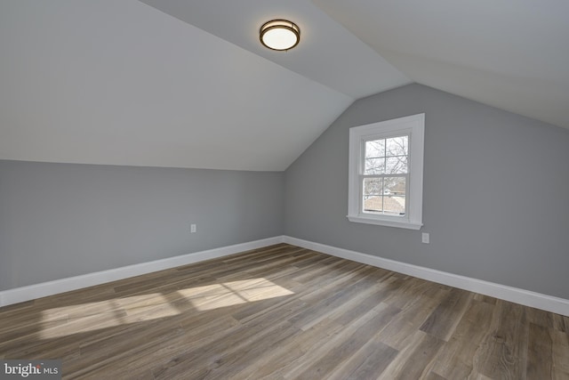 additional living space with vaulted ceiling and hardwood / wood-style flooring