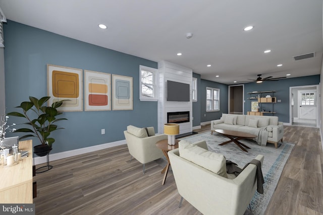 living room featuring ceiling fan, wood-type flooring, and a fireplace