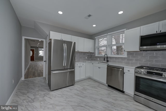 kitchen featuring appliances with stainless steel finishes, backsplash, white cabinetry, and sink