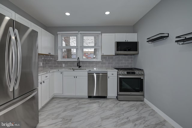 kitchen with light stone countertops, white cabinets, appliances with stainless steel finishes, and sink