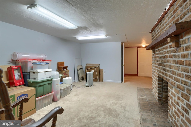 basement featuring a fireplace, brick wall, carpet flooring, and a textured ceiling