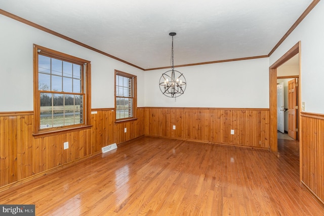 empty room featuring a chandelier, crown molding, and hardwood / wood-style flooring