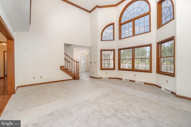 unfurnished living room featuring carpet, crown molding, and a high ceiling