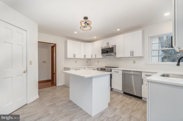 kitchen featuring stainless steel appliances, sink, pendant lighting, white cabinets, and a center island