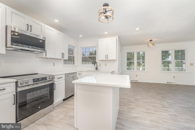 kitchen featuring a kitchen island, sink, white cabinetry, stainless steel appliances, and light tile patterned floors