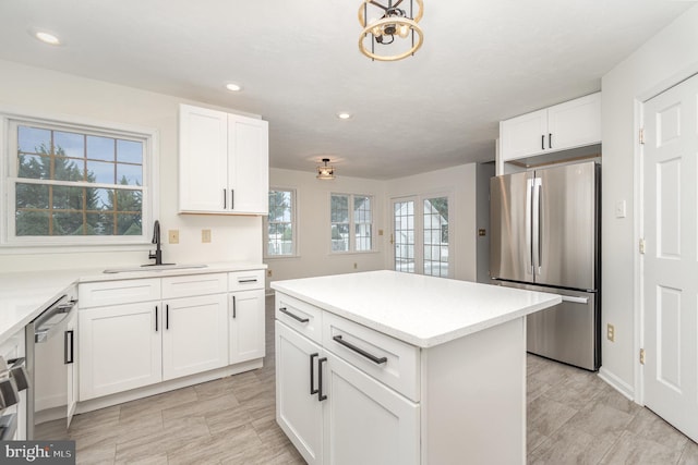 kitchen featuring appliances with stainless steel finishes, sink, white cabinetry, and a center island