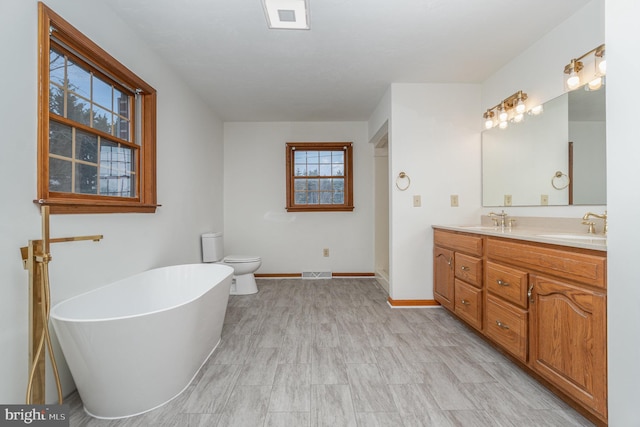 bathroom featuring toilet, vanity, and a bathing tub