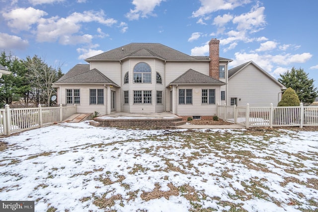 snow covered back of property featuring a patio