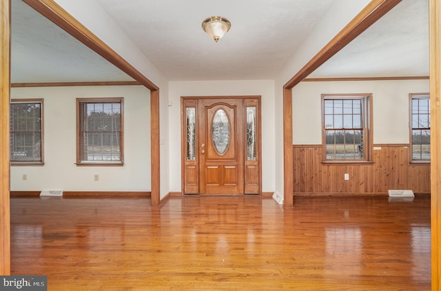 foyer entrance with ornamental molding and light hardwood / wood-style flooring