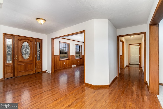 entryway featuring hardwood / wood-style flooring, a textured ceiling, and wooden walls