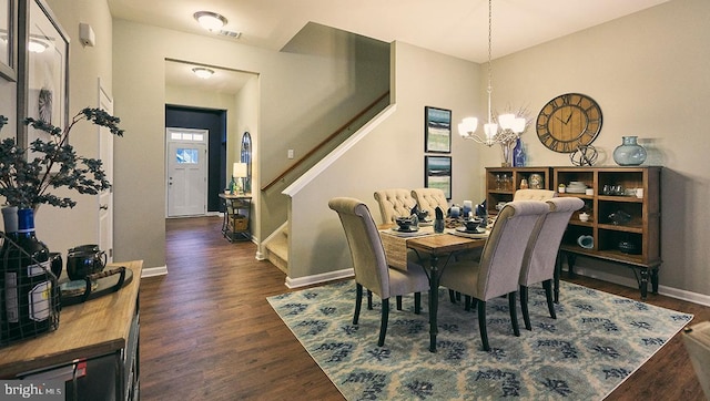 dining room with dark wood-type flooring and an inviting chandelier