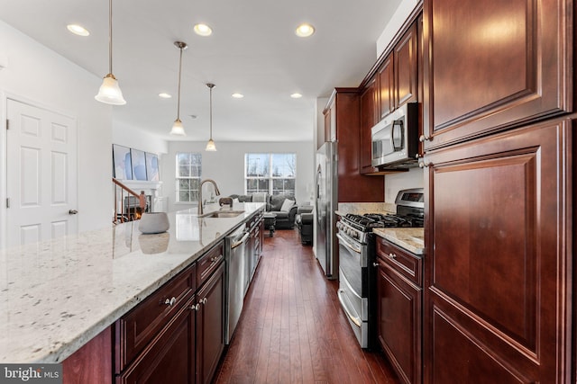 kitchen with sink, decorative light fixtures, stainless steel appliances, light stone counters, and dark hardwood / wood-style floors