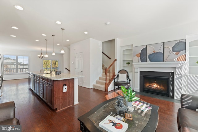 living room featuring built in features, an inviting chandelier, dark hardwood / wood-style floors, and sink