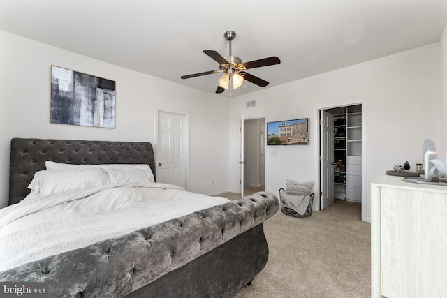 carpeted bedroom featuring a closet, ceiling fan, and a walk in closet