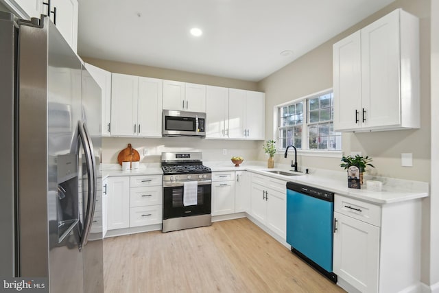 kitchen featuring white cabinetry, sink, stainless steel appliances, and light wood-type flooring