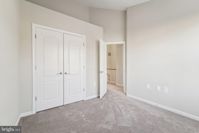 unfurnished bedroom featuring light colored carpet and a closet