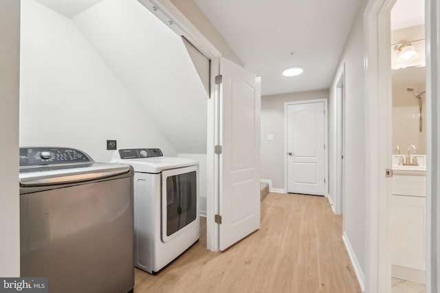 laundry area featuring separate washer and dryer, sink, and light hardwood / wood-style floors