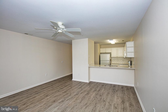 unfurnished living room featuring sink, hardwood / wood-style floors, and ceiling fan