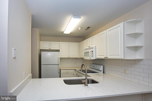 kitchen with white appliances, white cabinetry, decorative backsplash, sink, and light stone counters