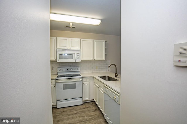 kitchen featuring white appliances, white cabinetry, sink, dark wood-type flooring, and backsplash