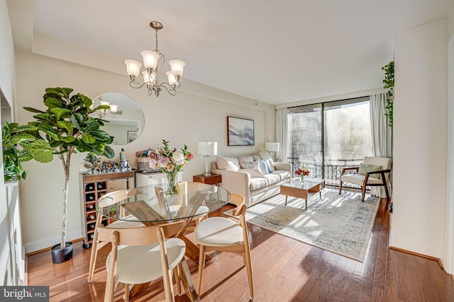 dining area with an inviting chandelier, baseboards, a wall of windows, and wood finished floors