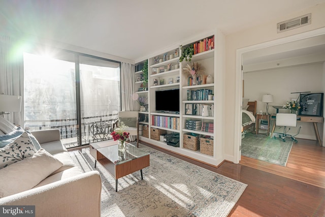 living area with visible vents and wood finished floors