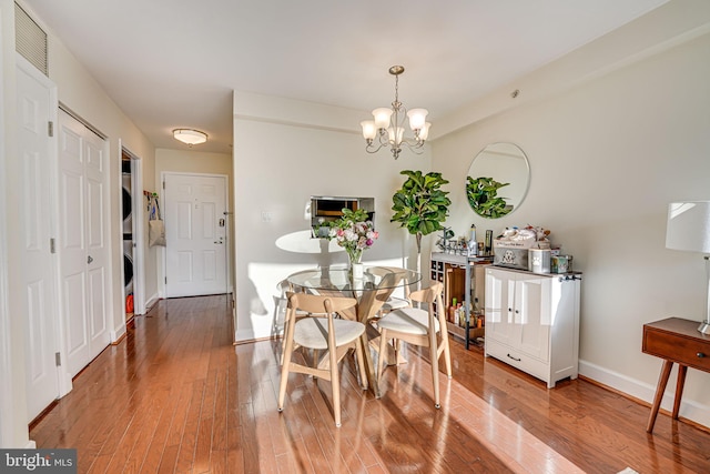 dining space featuring an inviting chandelier, baseboards, visible vents, and wood finished floors