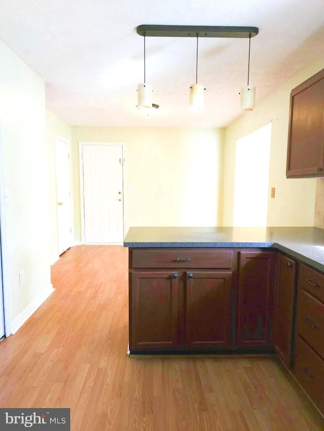 kitchen with light hardwood / wood-style flooring, kitchen peninsula, and decorative light fixtures