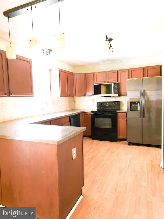 kitchen with tasteful backsplash, light hardwood / wood-style flooring, hanging light fixtures, and black appliances