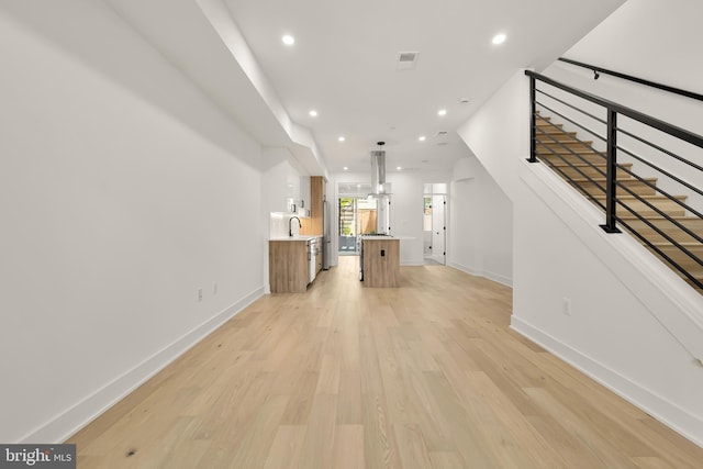 unfurnished living room featuring light hardwood / wood-style floors and sink