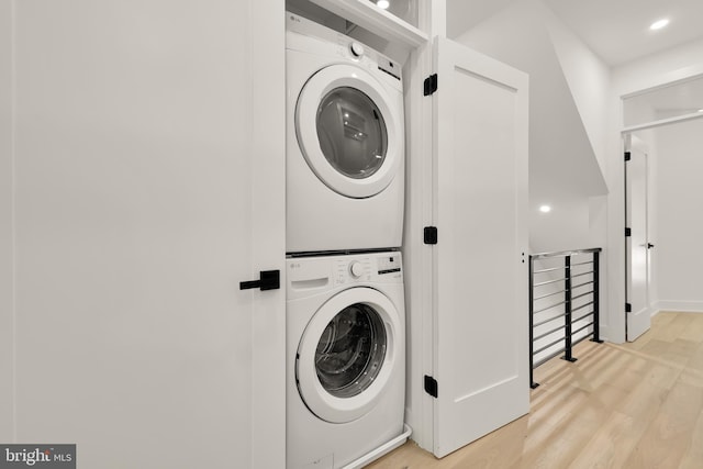 clothes washing area with stacked washer and dryer and light wood-type flooring