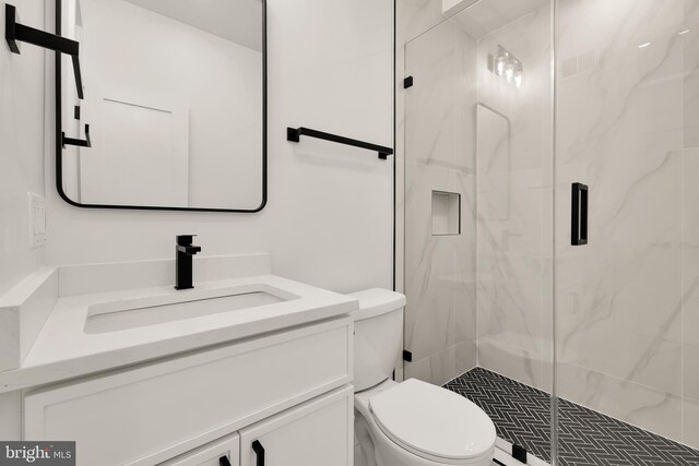 bathroom with toilet, a shower with shower door, and vanity