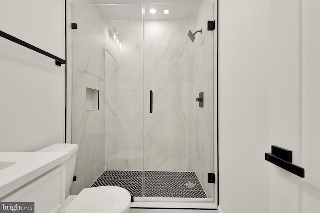 bathroom featuring a shower with shower door, toilet, and vanity