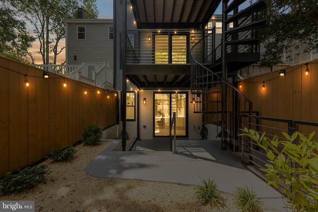 back house at dusk featuring a patio