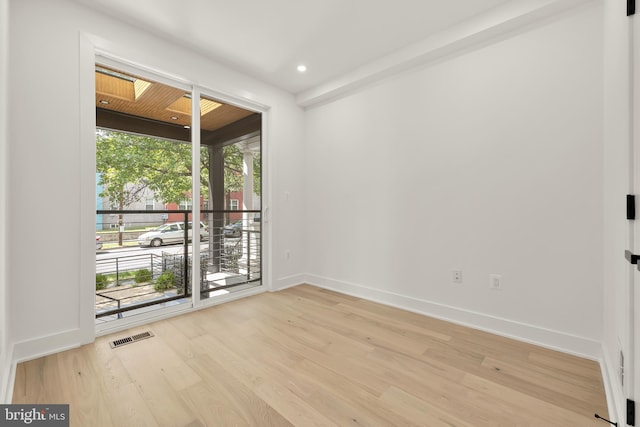 empty room featuring a skylight and light wood-type flooring