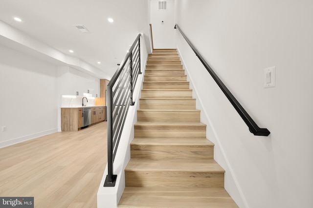 staircase featuring sink and hardwood / wood-style floors