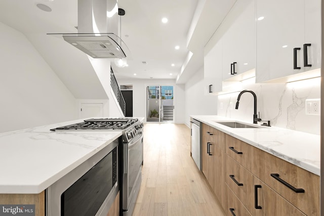 kitchen with white cabinetry, island exhaust hood, stainless steel appliances, sink, and light stone counters