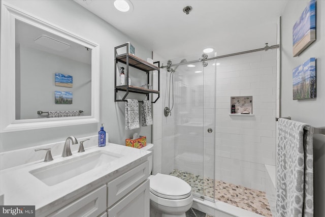 bathroom featuring a shower with door, toilet, and vanity