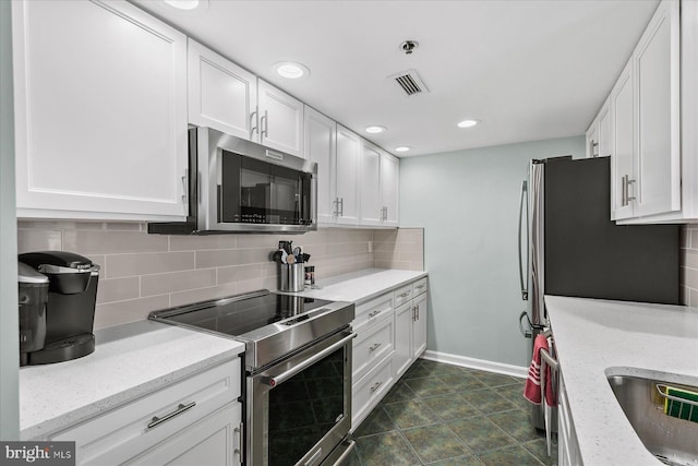 kitchen with appliances with stainless steel finishes, sink, white cabinets, backsplash, and light stone counters