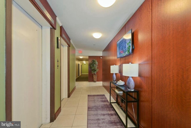 corridor with wooden walls and light tile patterned flooring