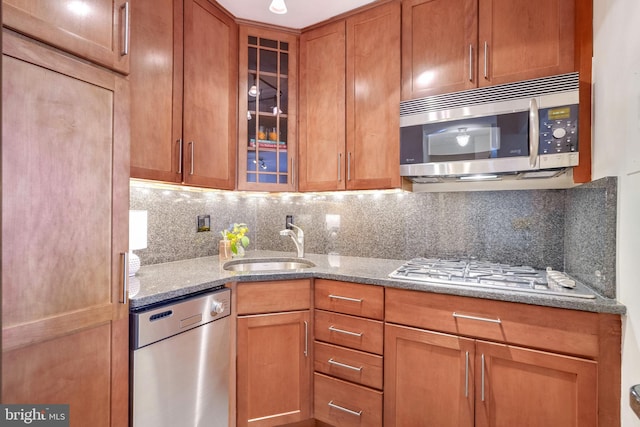 kitchen with tasteful backsplash, appliances with stainless steel finishes, sink, and dark stone counters