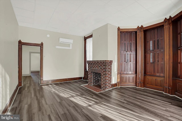 unfurnished living room featuring dark wood-type flooring, a fireplace, and a wall unit AC