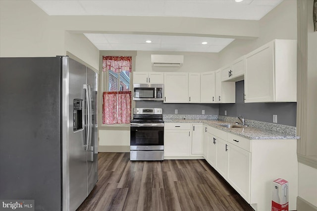 kitchen featuring appliances with stainless steel finishes, light stone counters, a wall mounted air conditioner, white cabinets, and dark hardwood / wood-style flooring