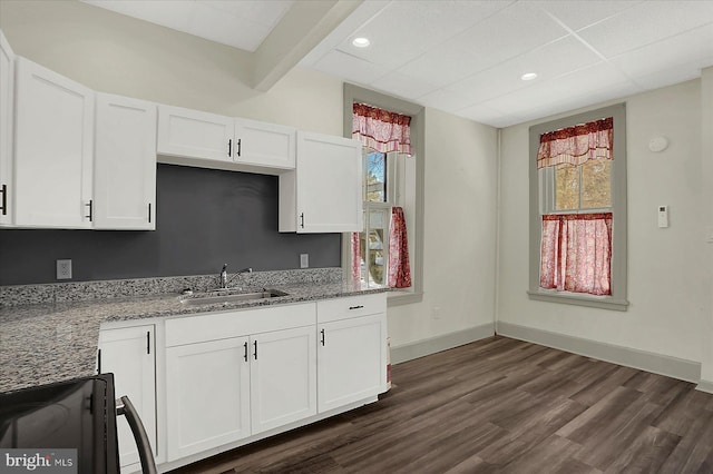 kitchen with white cabinetry, sink, beam ceiling, and light stone countertops