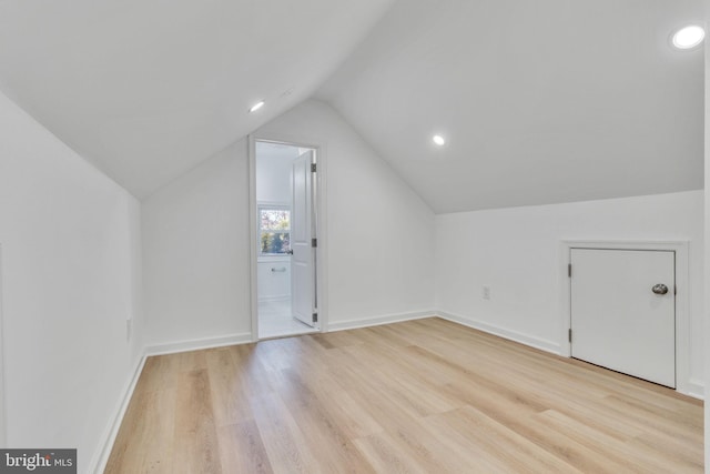 additional living space featuring vaulted ceiling and light wood-type flooring