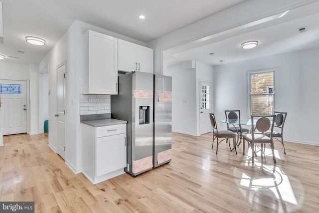 kitchen featuring white cabinetry, stainless steel fridge with ice dispenser, light hardwood / wood-style flooring, and backsplash